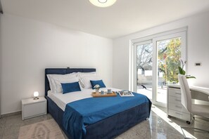 A bedroom with a bed, bedside table, and a desk with a chair. - Apartment Ayni With Private Pool (Umag)