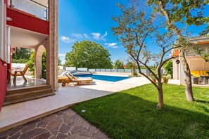 A pool area with a clear sky, a tree, and a stone pathway. - Apartment Ayni With Private Pool (Umag)