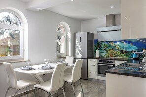 A modern kitchen with white cabinetry, a stainless steel refrigerator, and a large fish tank. - Apartment Ayni With Private Pool (Umag)