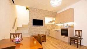 Een moderne keuken met houten kastjes, een inbouwoven en een flatscreen televisie aan de wand.