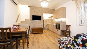 Een kleine woonruimte met een eethoek, kitchenette en een slaapbank.