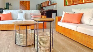 A living room with a sofa, two small tables, and wicker baskets.