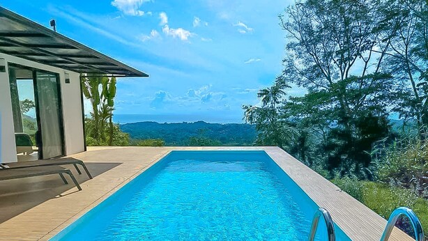 A rectangular swimming pool with clear blue water, surrounded by a wooden deck.