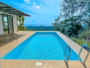 A rectangular swimming pool with clear blue water, surrounded by a wooden deck. - Casa Syano (Ciudad Cortés)