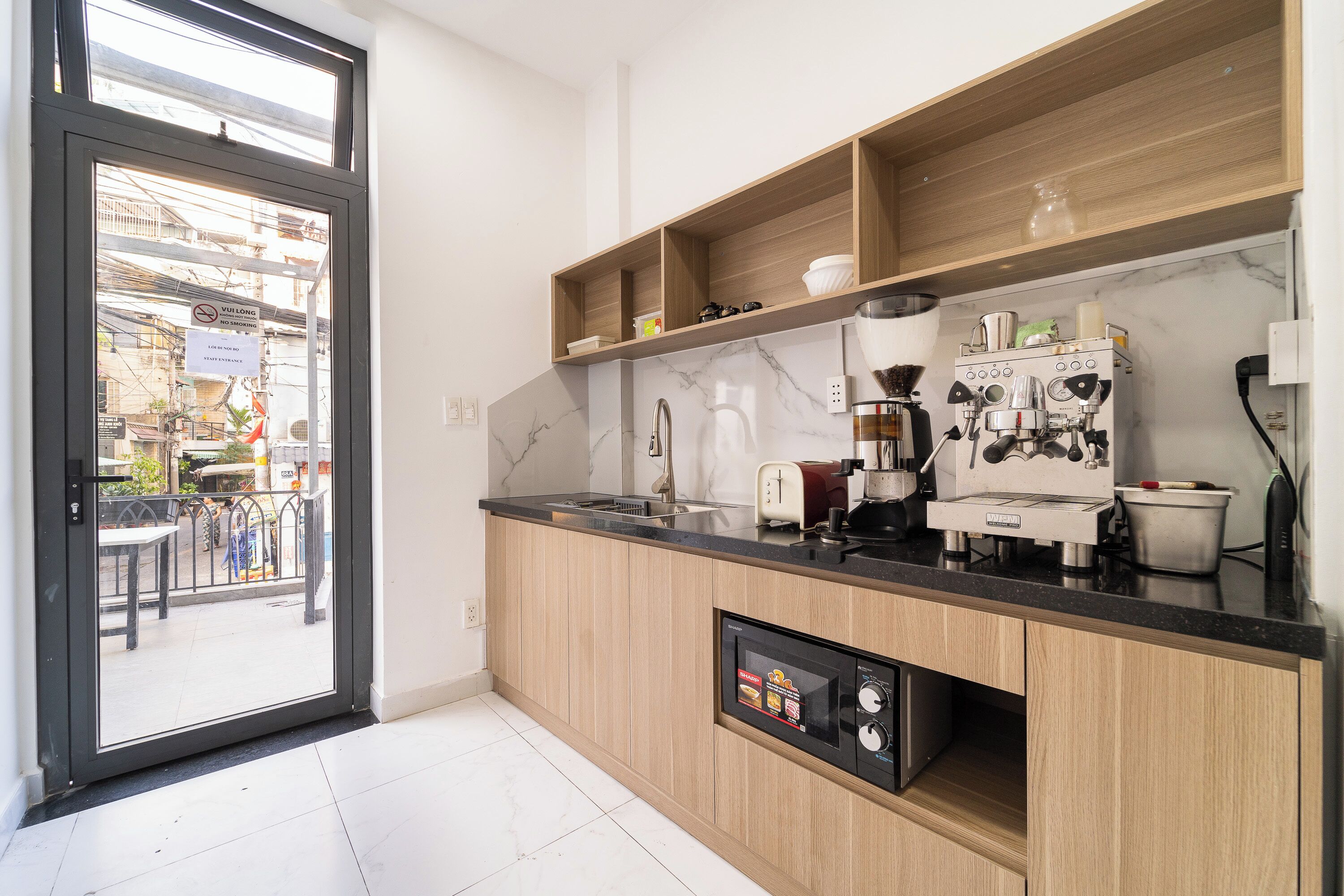 Una cucina moderna con una macchina per espresso integrata, un lavello e scaffali in legno.