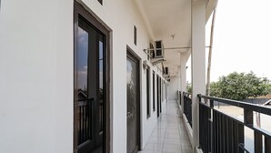 A corridor with a tiled floor, black railings, and windows with black frames. - SPOT ON 3859 Sweet Candy 2NearResinda park mall (Karawang)