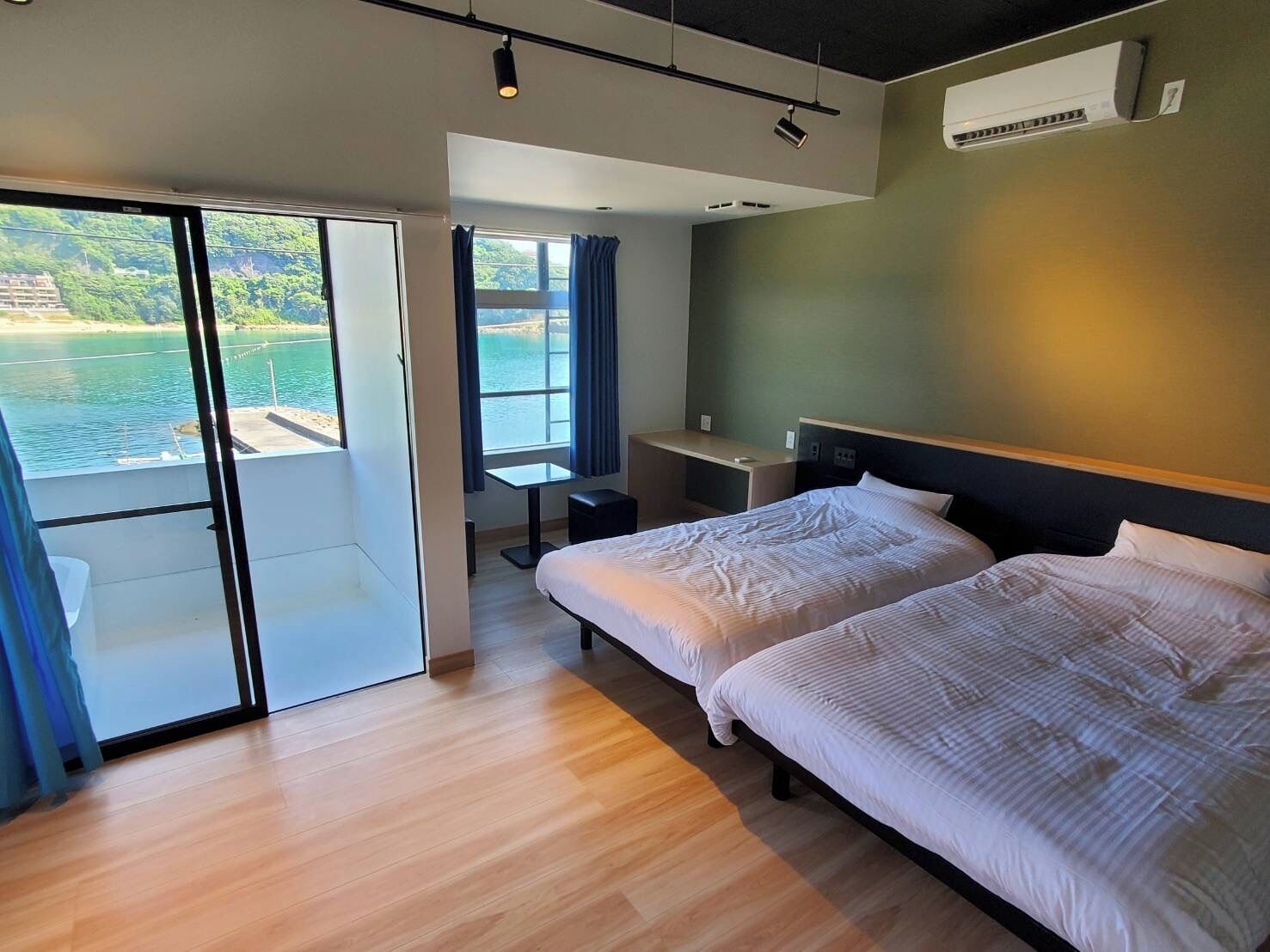 Ein modernes Hotelzimmer mit einer großen Schiebeglasdoor zu einem Balkon mit Meerblick.