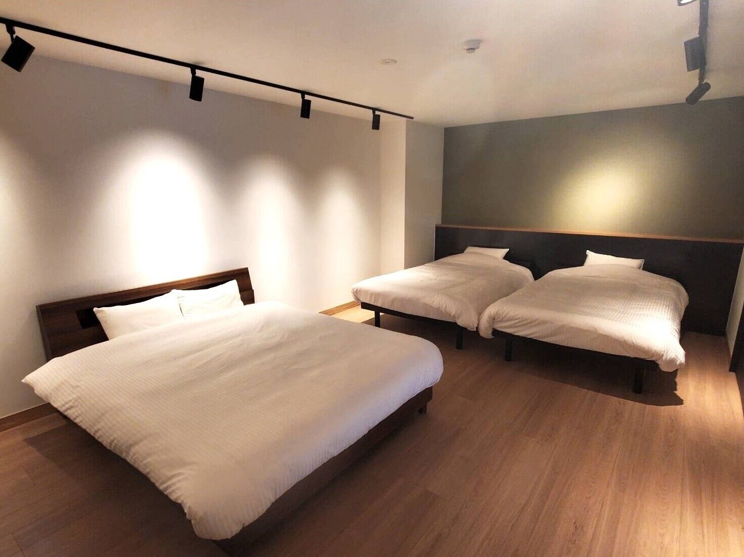 Ein Hotelzimmer mit zwei Betten, Holzboden und modernem Design.