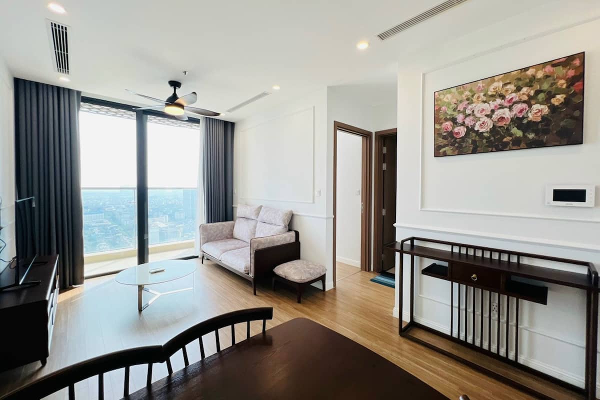 A modern living room with a sofa, a dining table, and a painting.