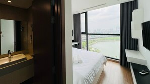 Habitación de hotel con una cama grande, televisión, escritorio y baño con lavamanos y espejo.