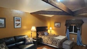 Een knus ingerichte kamer met een bed, een slaapbank en een lamp.