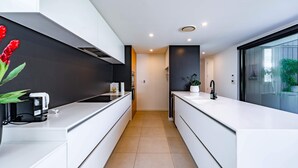 A modern kitchen with white cabinetry, a black backsplash, and a large window.