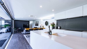 A modern kitchen with a large island, white cabinetry, and a dining area with chairs.