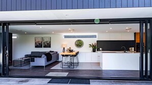A modern open-plan living area with a sofa, dining table, and kitchen.