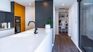 A modern kitchen with a white countertop, built-in oven, and a sleek faucet.