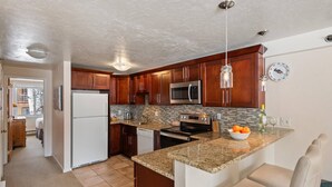 A modern kitchen with granite countertops, stainless steel appliances, and wooden cabinets. - 50 Yards to Snowmass Trails! Walk to Shops/Dining, Pool, Hot Tub & Fitness Room (Snowmass Village)
