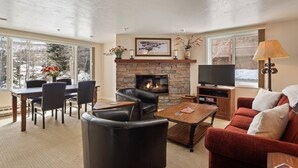 A cozy living room with a stone fireplace, a television, and comfortable seating. - 50 Yards to Snowmass Trails! Walk to Shops/Dining, Pool, Hot Tub & Fitness Room (Snowmass Village)