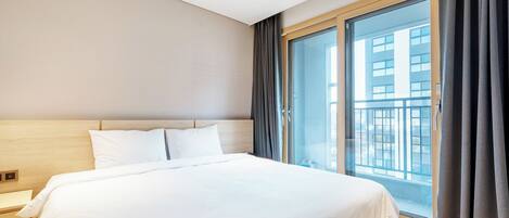 Een hotelkamer met een groot bed, een nachtkastje en een schuifdeur die leidt naar een balkon.