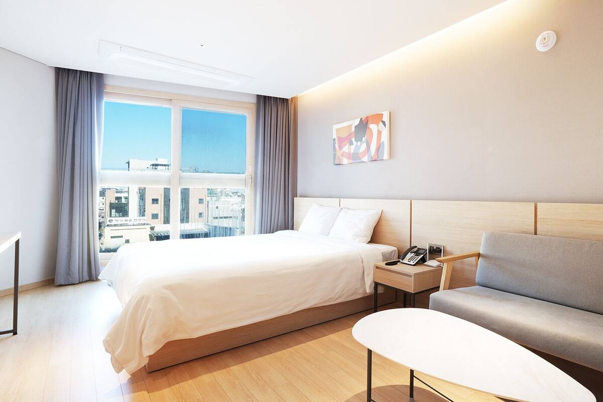 A hotel room with a bed, bedside table, and a sofa.