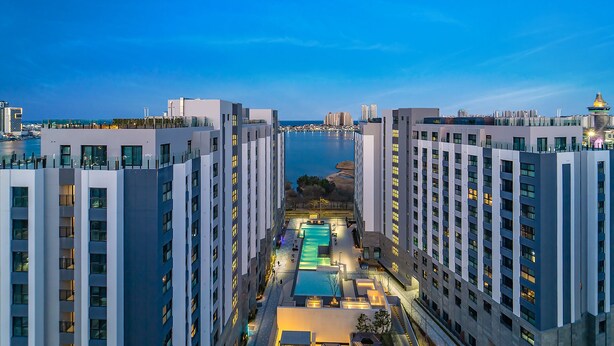 A high-rise hotel with a central pool, multiple balconies, and a view of the sea. - Dominiclava Sokco (Sokcho)
