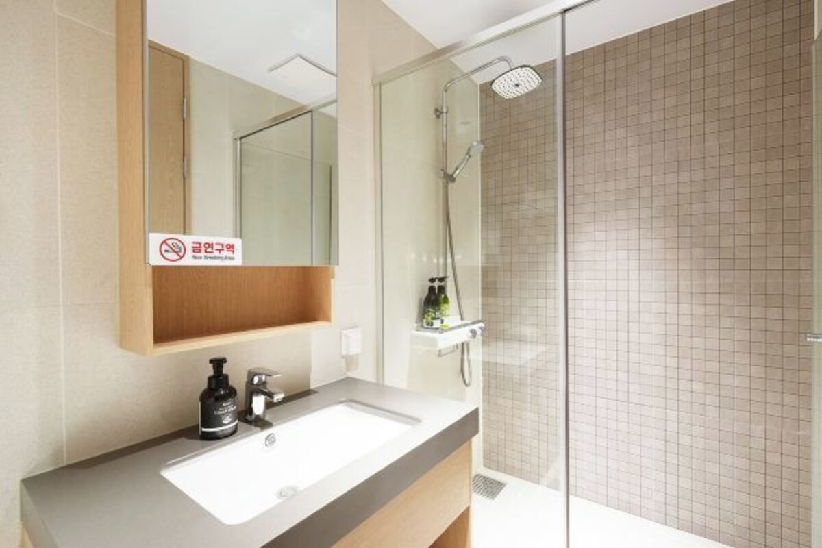 A modern bathroom with a sink, mirror, and shower.