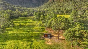 Un chalet isolé, entouré d’une végétation luxuriante et de montagnes.