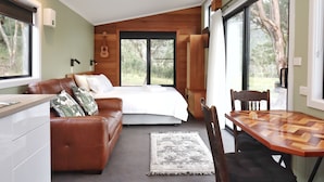 Une chambre à coucher avec un lit, un canapé en cuir marron, une table à manger et une grande fenêtre.