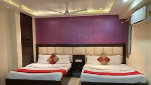 A bedroom with two beds, a ceiling fan, and an air conditioning unit. - HOTEL MAHAMAYA PALACE (Deoghar)