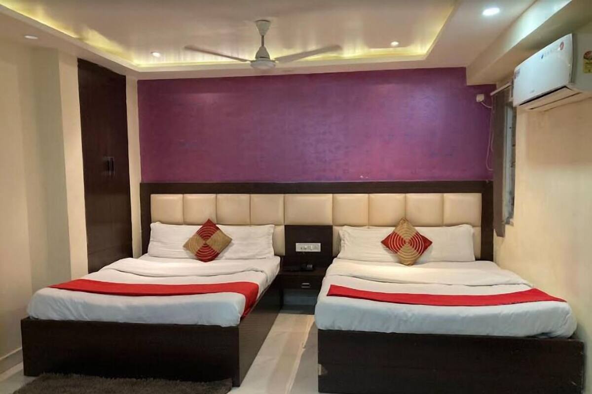 A bedroom with two beds, a ceiling fan, and an air conditioning unit.