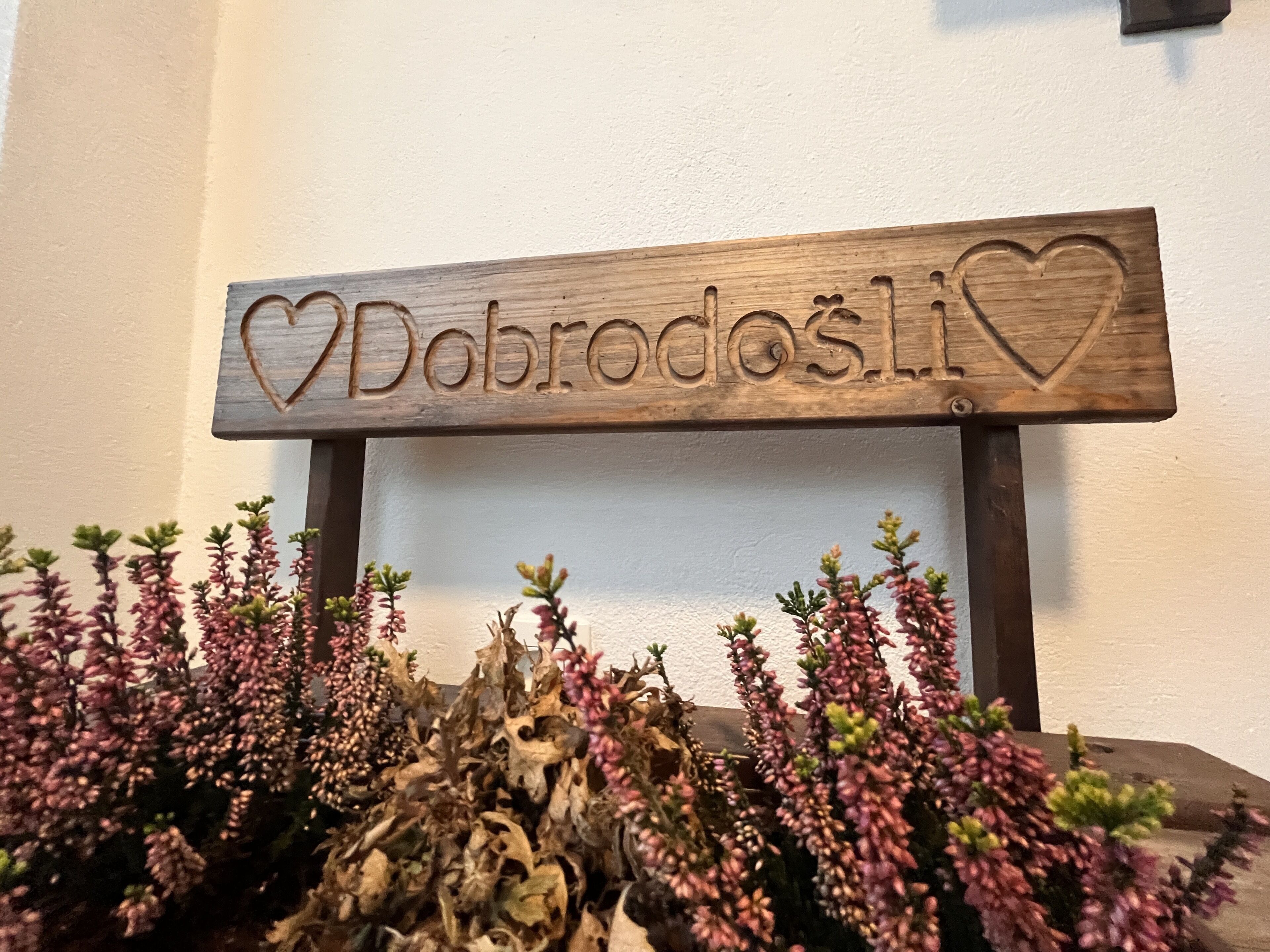 A wooden sign with the name "Dobrodosli" and a heart symbol.