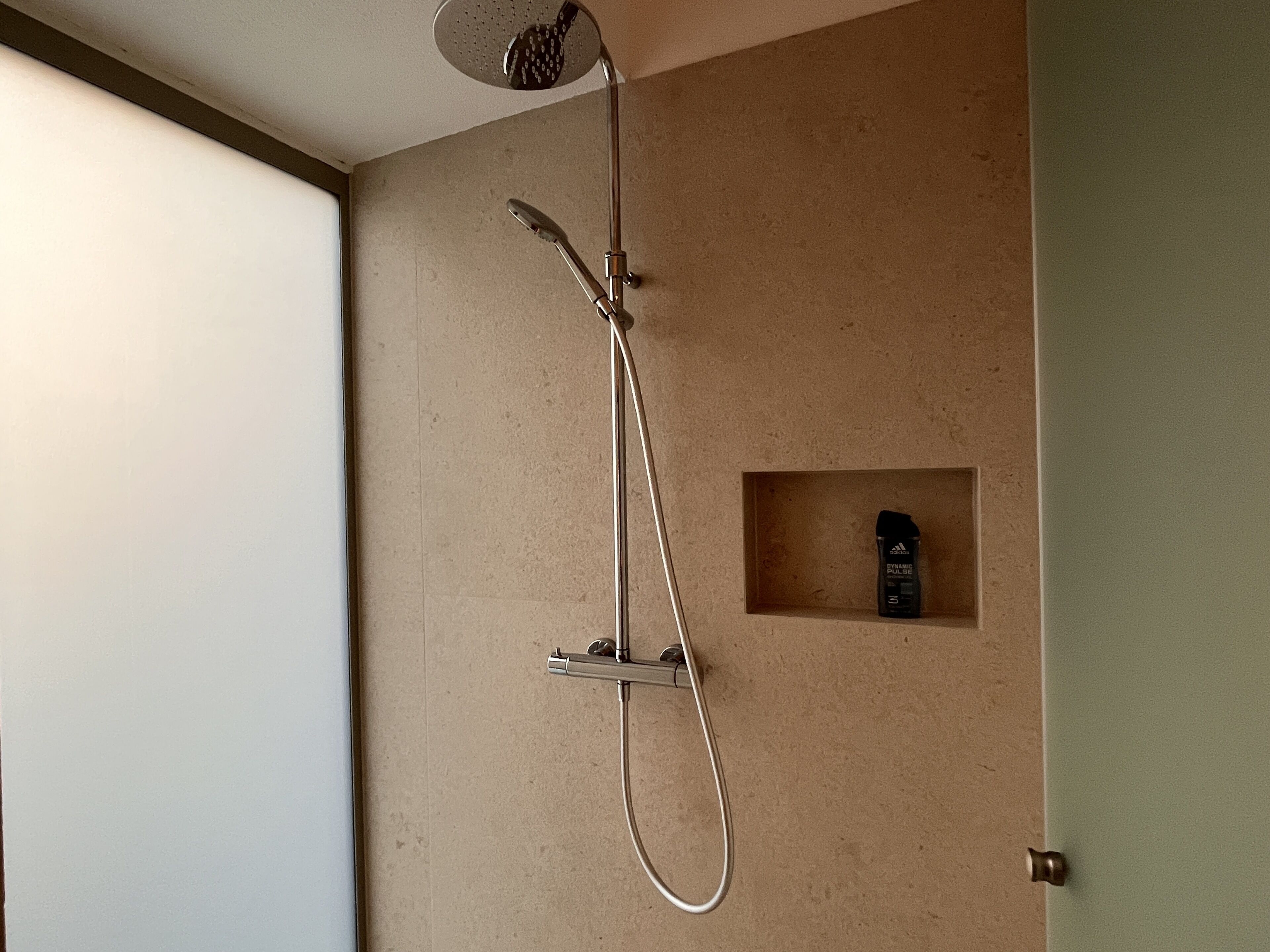 A shower with a handheld showerhead and a wall-mounted faucet.