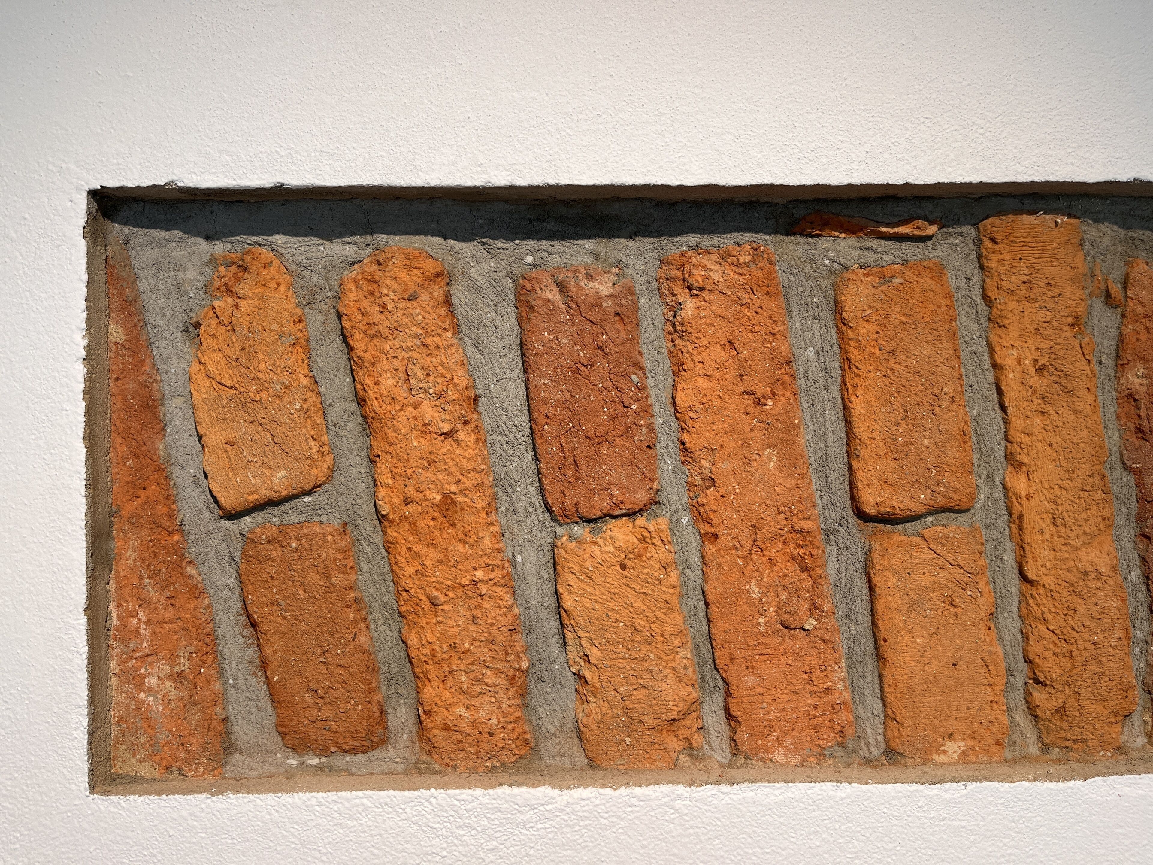 Primer plano de un muro de ladrillo con una abertura rectangular.