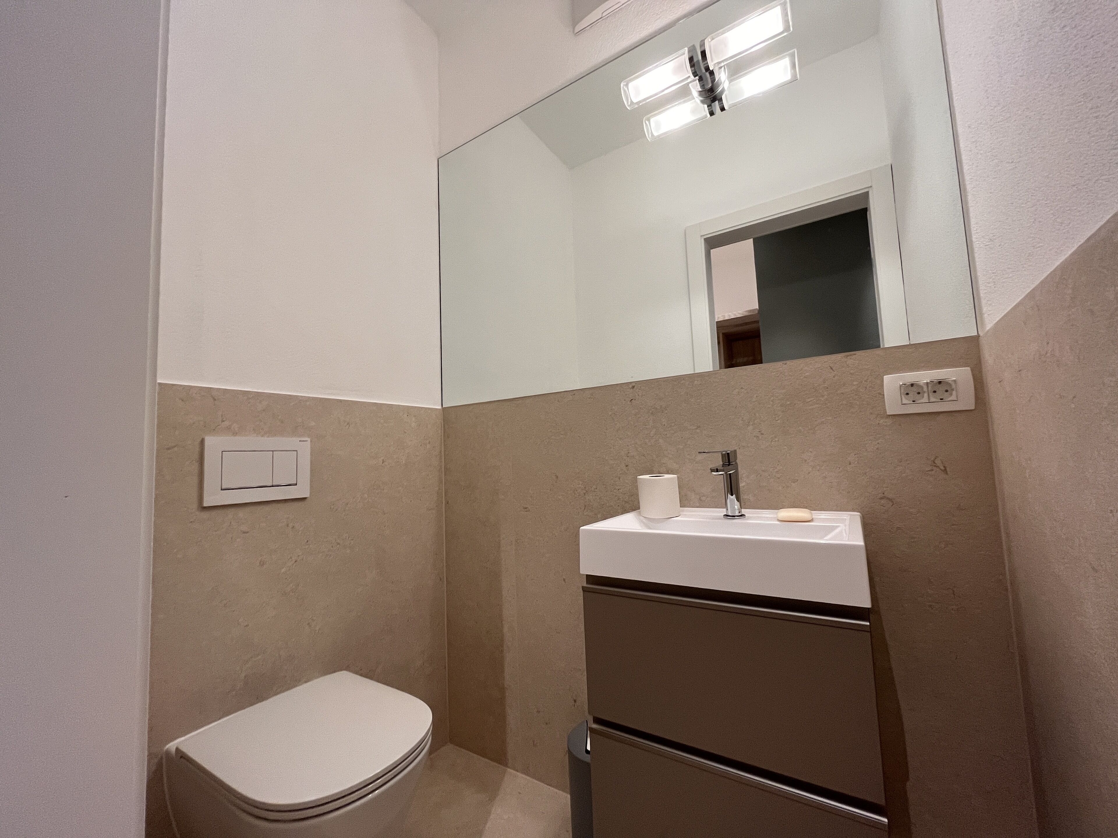 Un baño pequeño con inodoro, lavabo y espejo.