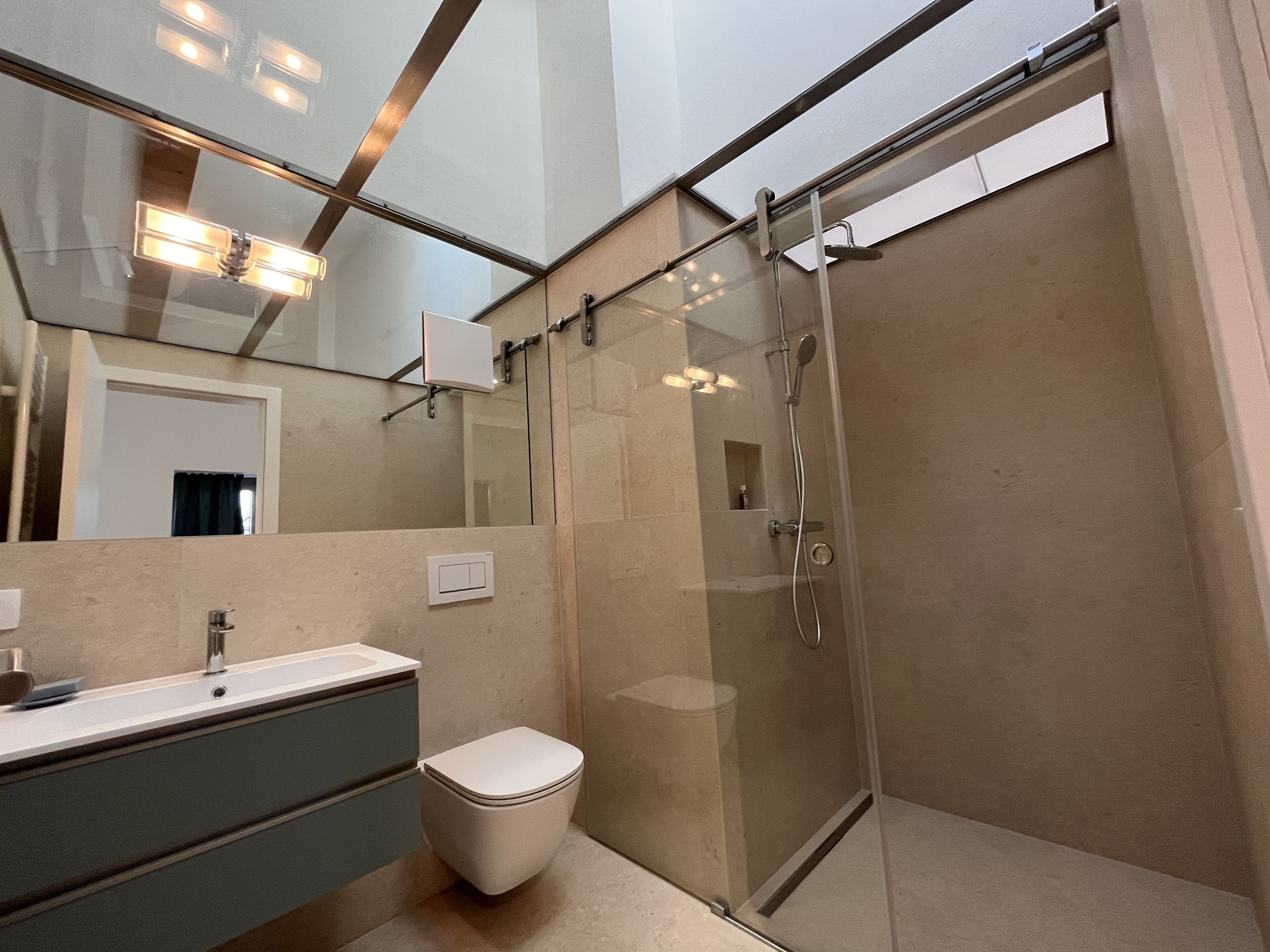 A modern bathroom with a glass-enclosed shower, a sink with a mirror, and a toilet.