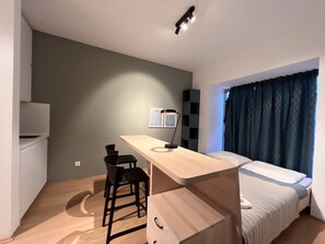 Cozy retreat with a single bed, desk, and wall-mounted lamp.