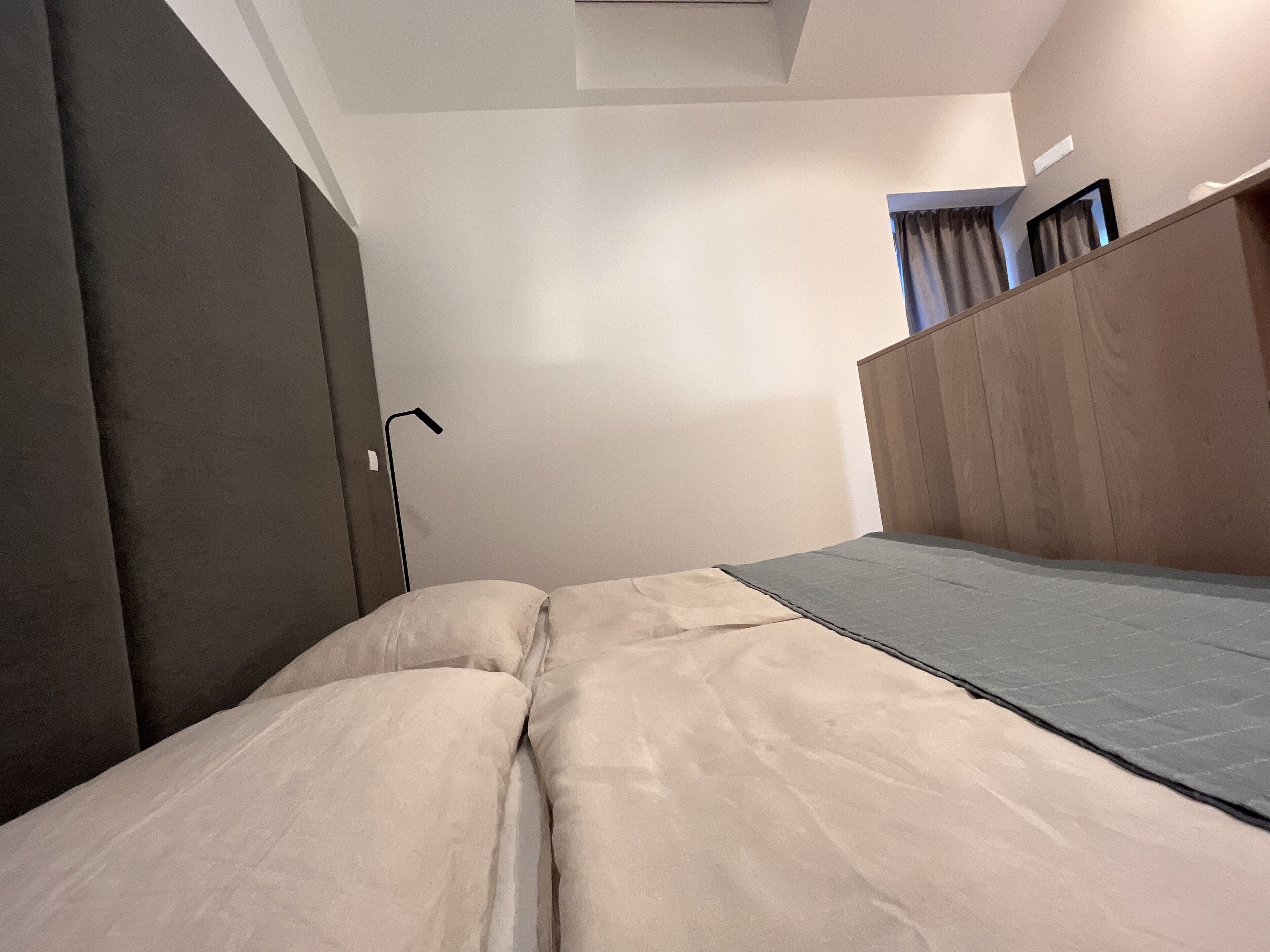 Een slaapkamer met een bed, nachtkastje, lamp en kledingkast.