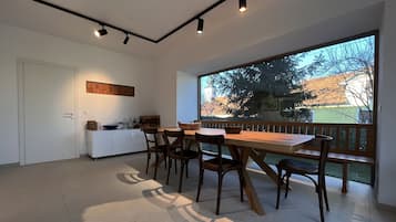 Una cocina moderna con un ventanal grande, un área de comedor con mobiliario de madera y vistas a un balcón con barandilla.