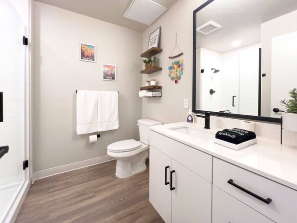 Un baño moderno con inodoro, lavamanos, espejo y armarios de almacenamiento.