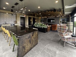Una cocina moderna con una isla central, un comedor con sillas y una zona de estar con sofá y sillones.