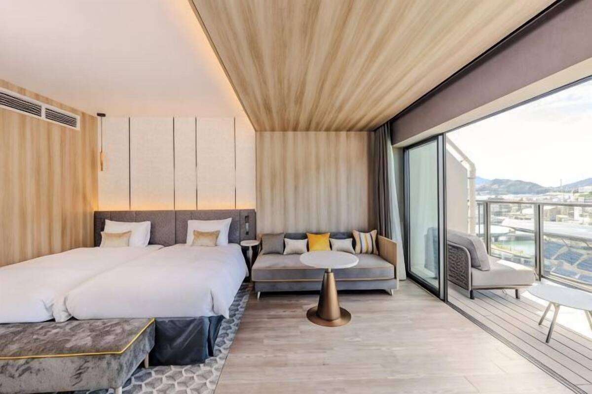 Camera d'albergo moderna con letto, divano e balcone vista città.