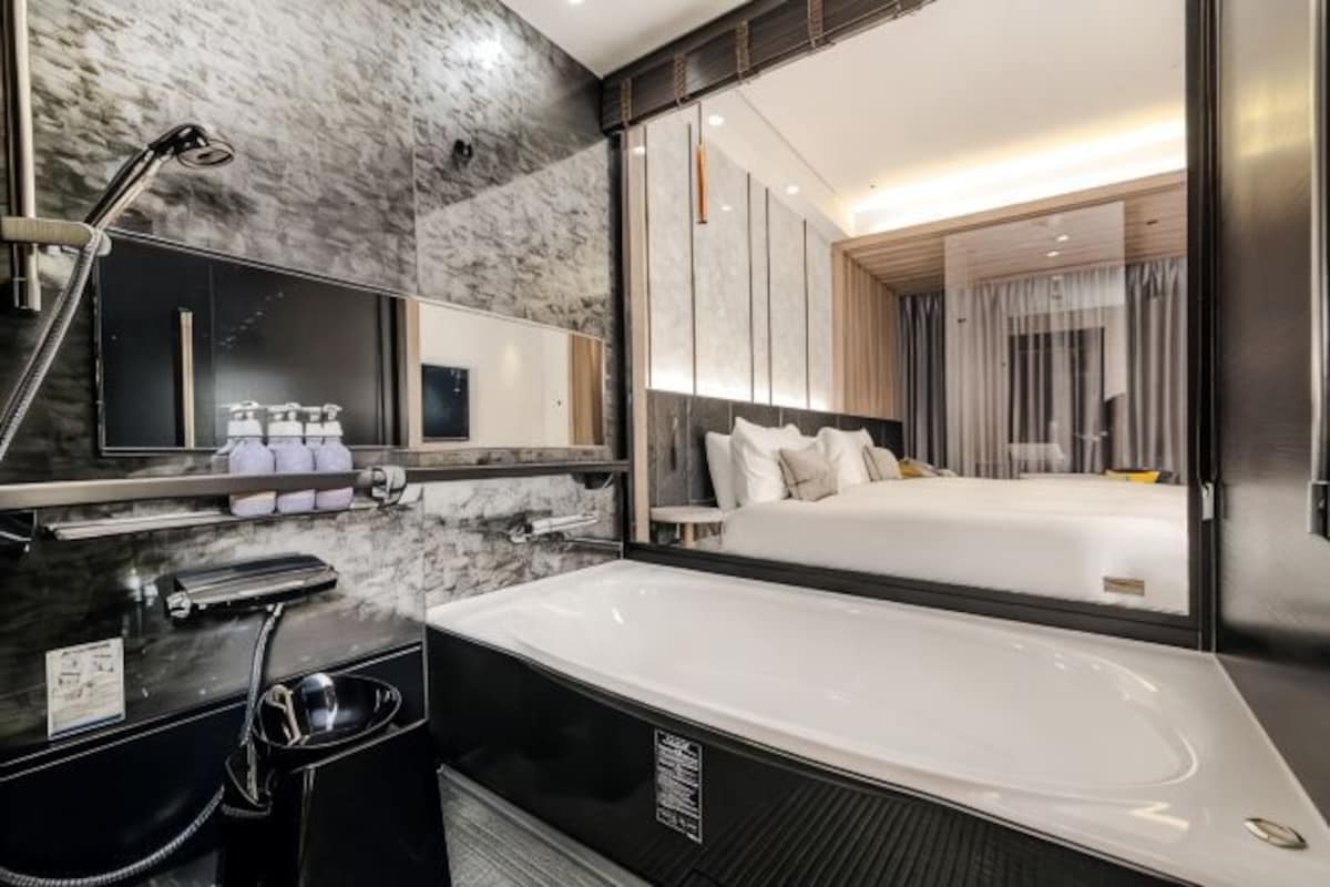 Een moderne hotelbadkamer met een groot bad, een spiegel en een wastafel met toiletartikelen.