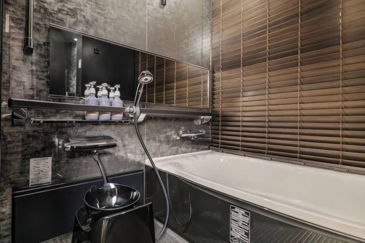 Un bagno con una vasca, uno specchio, uno scaffale con articoli da toilette e un soffione.