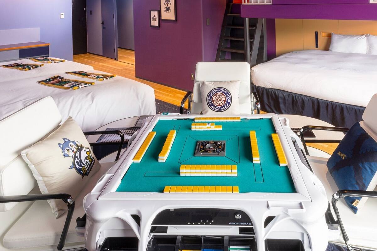 Una camera d'albergo con due letti, una scrivania con un gioco da tavolo e una sedia con un cuscino.