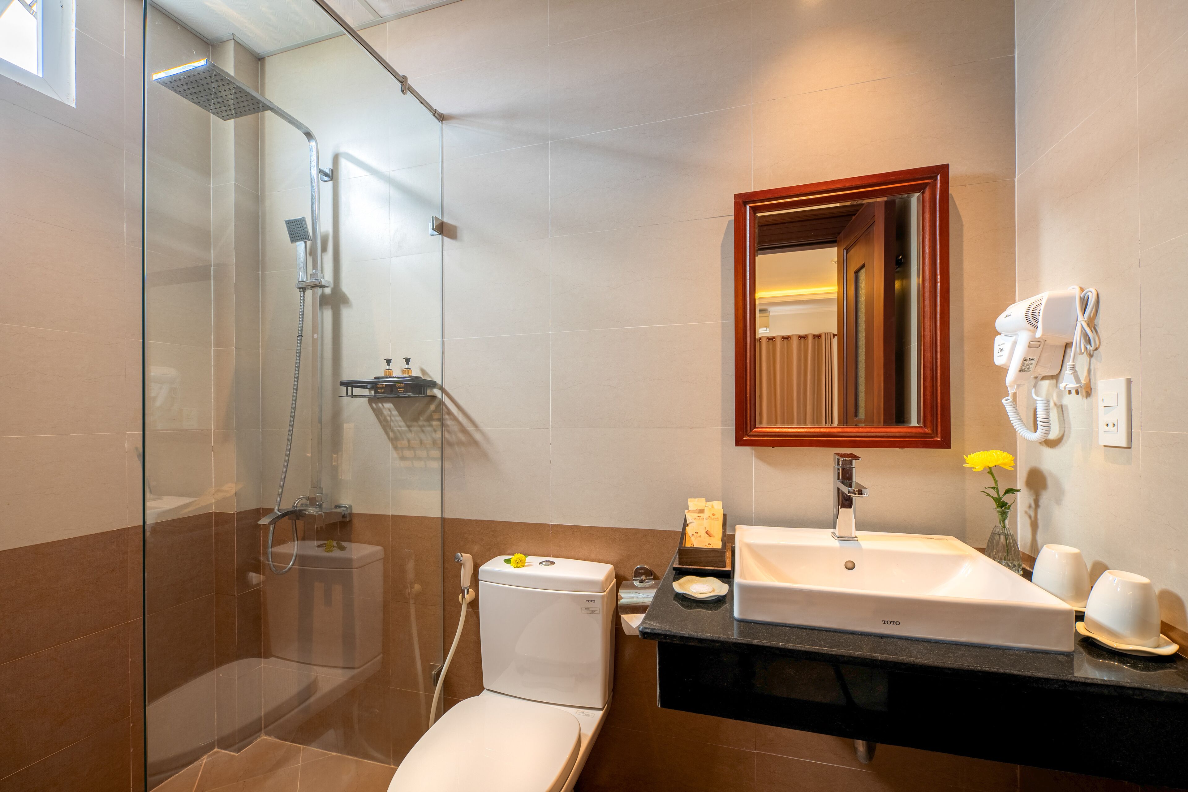 Un baño moderno con ducha envuelta en vidrio, inodoro blanco, lavabo con espejo y toallero.