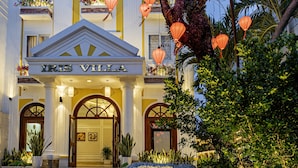 A grand hotel entrance with a stone monument, a well-lit facade, and a staircase leading up to the doors. - Iris De Villa Hoi An (Da Nang)
