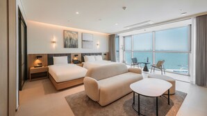 A modern hotel room with a large bed, a sofa, a small table, and a view of the sea. - WAVE M HOTEL WEST (Siheung)