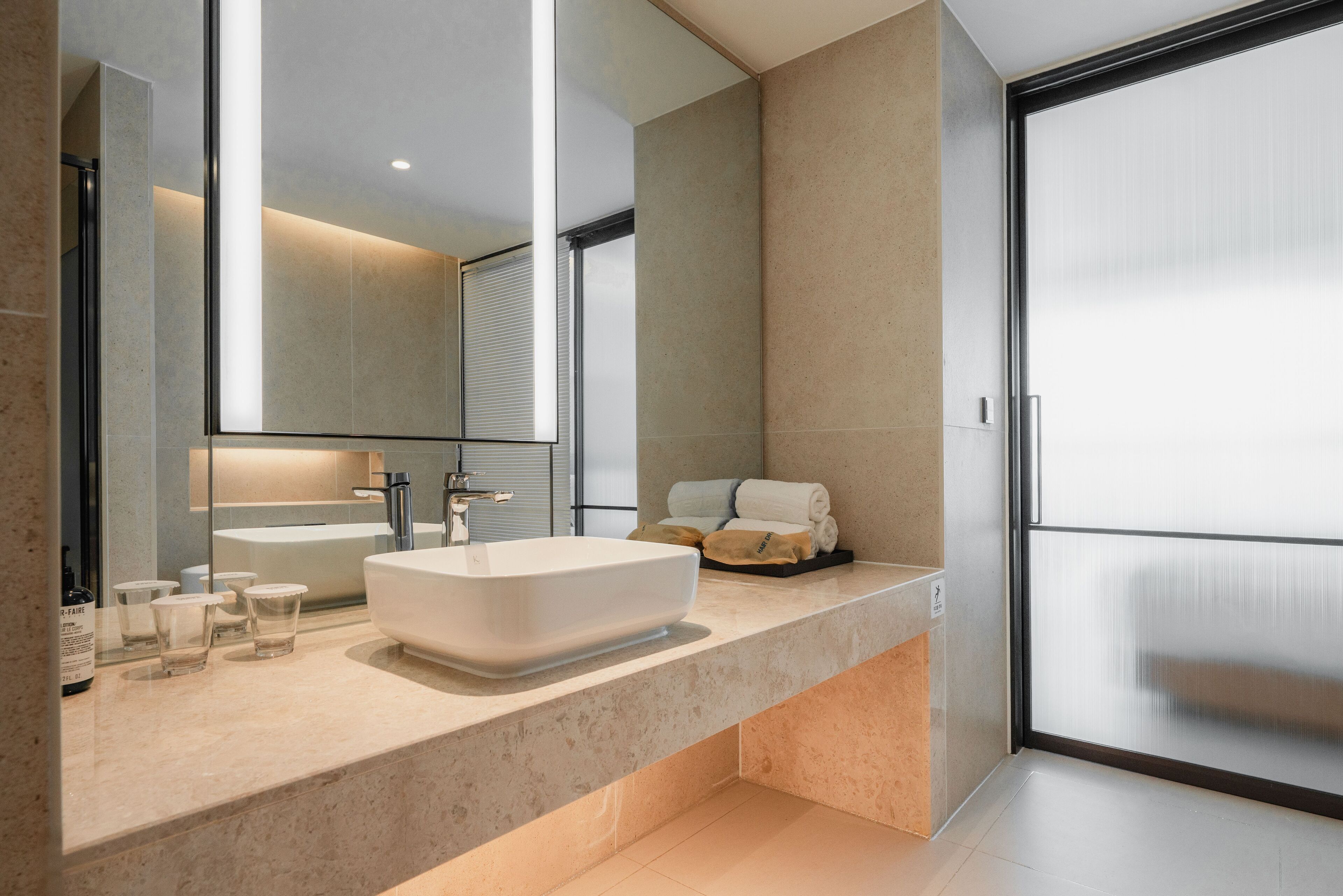 A modern bathroom with a large mirror, a white sink, and a glass shower enclosure.