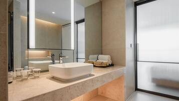 A modern bathroom with a large mirror, a white sink, and a glass shower enclosure.