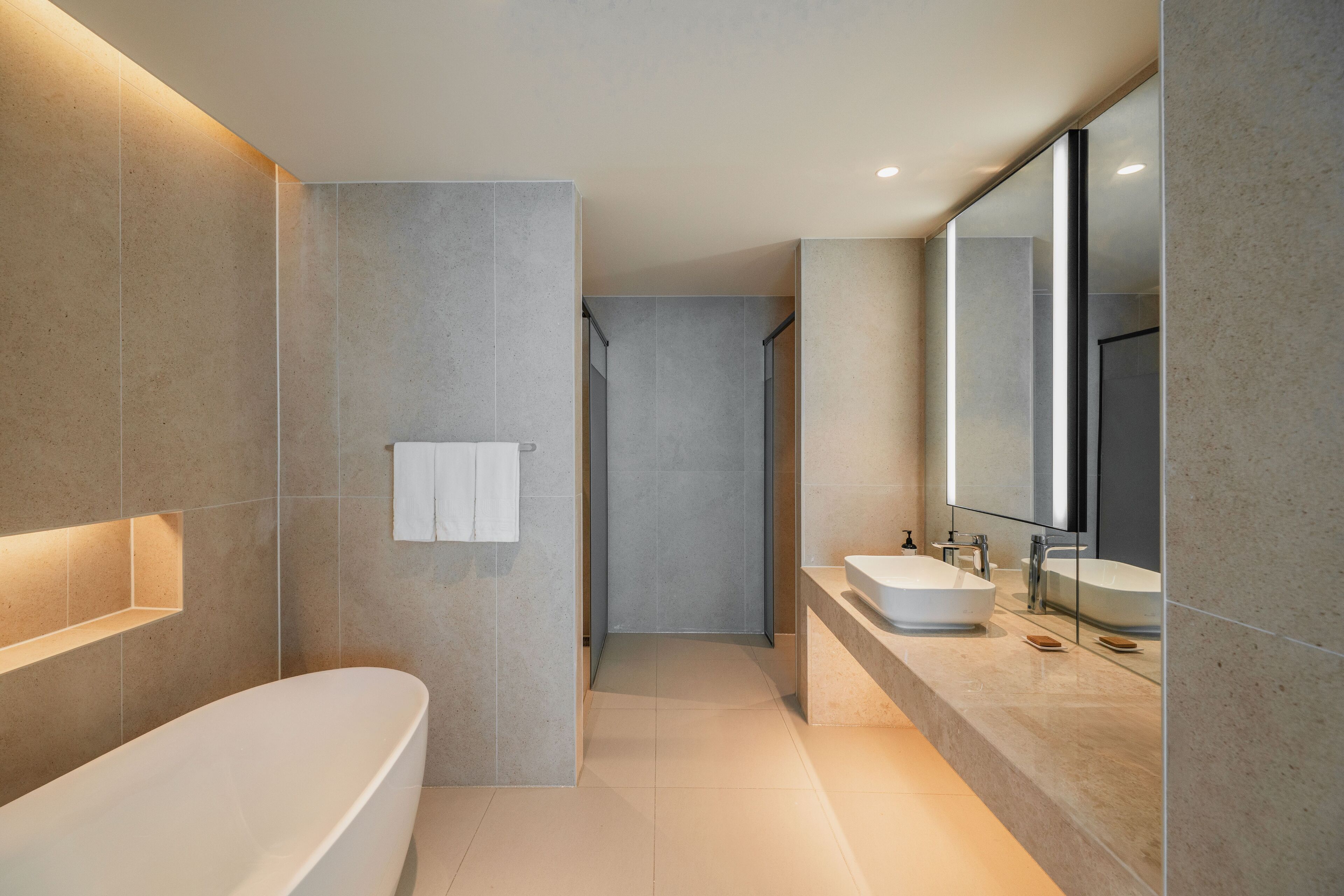 A modern bathroom with a freestanding bathtub, a walk-in shower, and a large mirror above the sink.