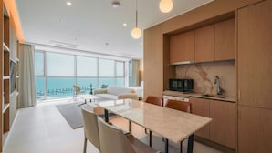 A modern hotel room with a dining area, kitchen, and large windows offering a view of the sea. - WAVE M HOTEL WEST (Siheung)
